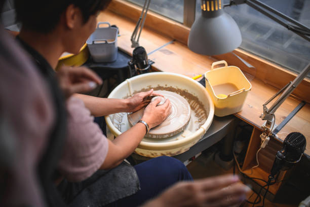 Cropped image of potter molding shape on wheel. Close-up of craftsperson working. He is making clay pot.