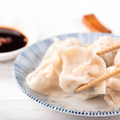 Fresh, delicious boiled pork, shrimp gyoza dumplings on white background with soy sauce and chopsticks, close up, lifestyle. Homemade design concept.